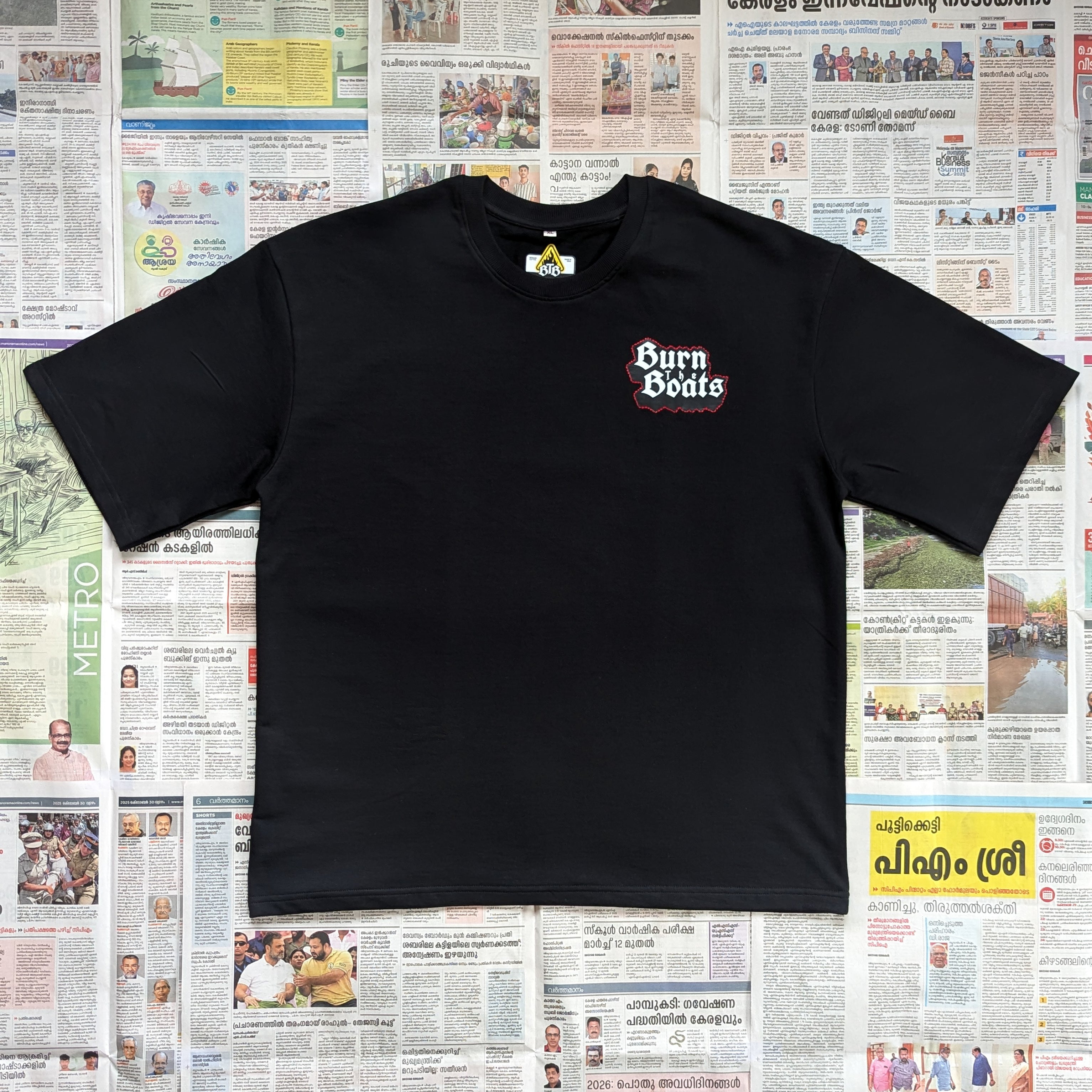 Black oversized tshirt with 'Burn the Boats' text/logo in the front left chest area